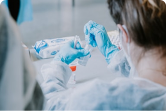 A person wearing blue latex gloves works in a laboratory, handling scientific samples.